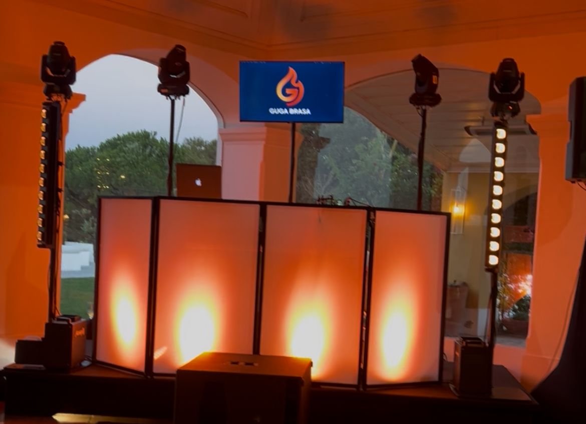 Cabine de DJ Team Brasa com ecrã de logótipo e luzes, montada para uma festa de empresa