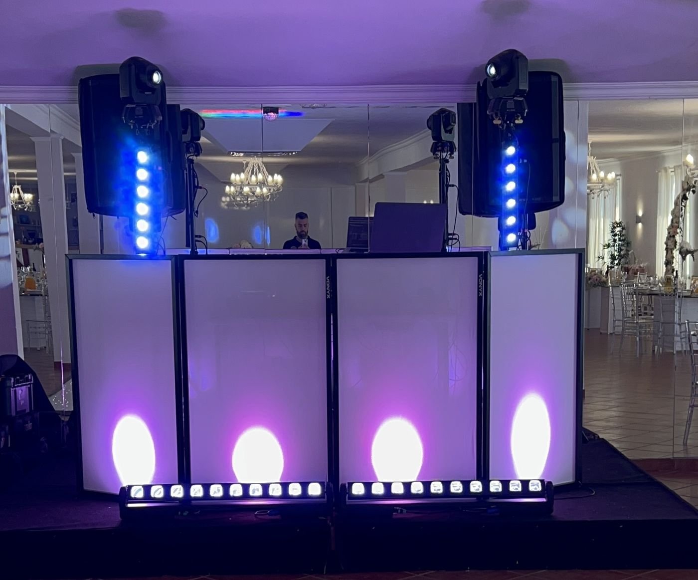 Cabine de DJ com colunas, luzes roxas e barras de LED num salão