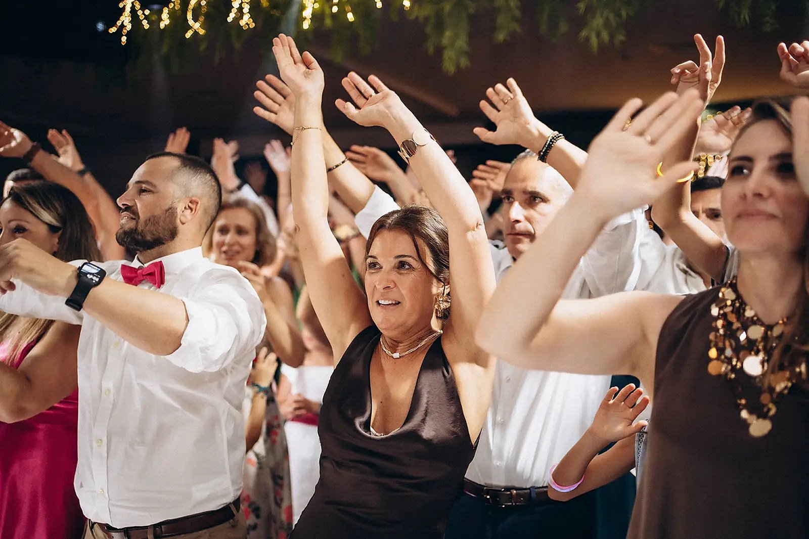 Convidados de mãos no ar numa pista de casamento animada