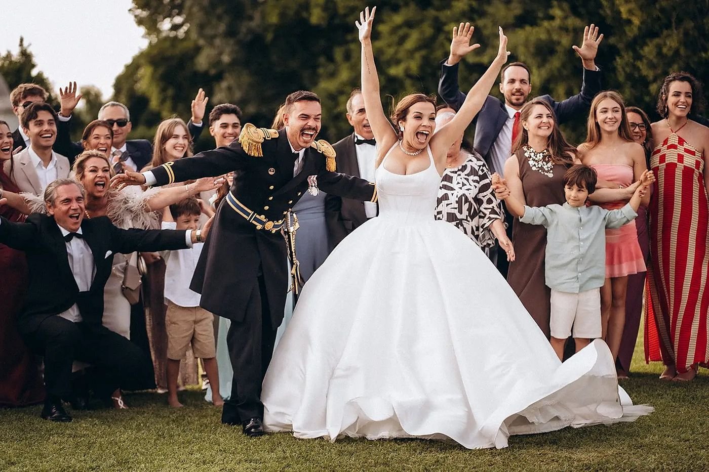 Bride, groom and guests celebrating in a garden in Portugal, arms in the air