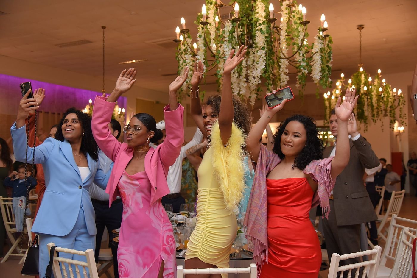 Convidadas de braços no ar numa festa de casamento
